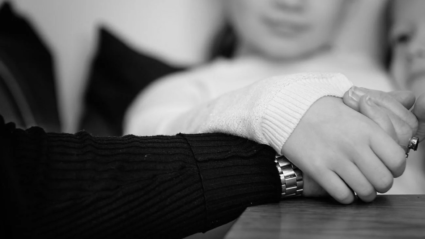 Närbild på två personer som håller varandras händer, från Världscancerdagen